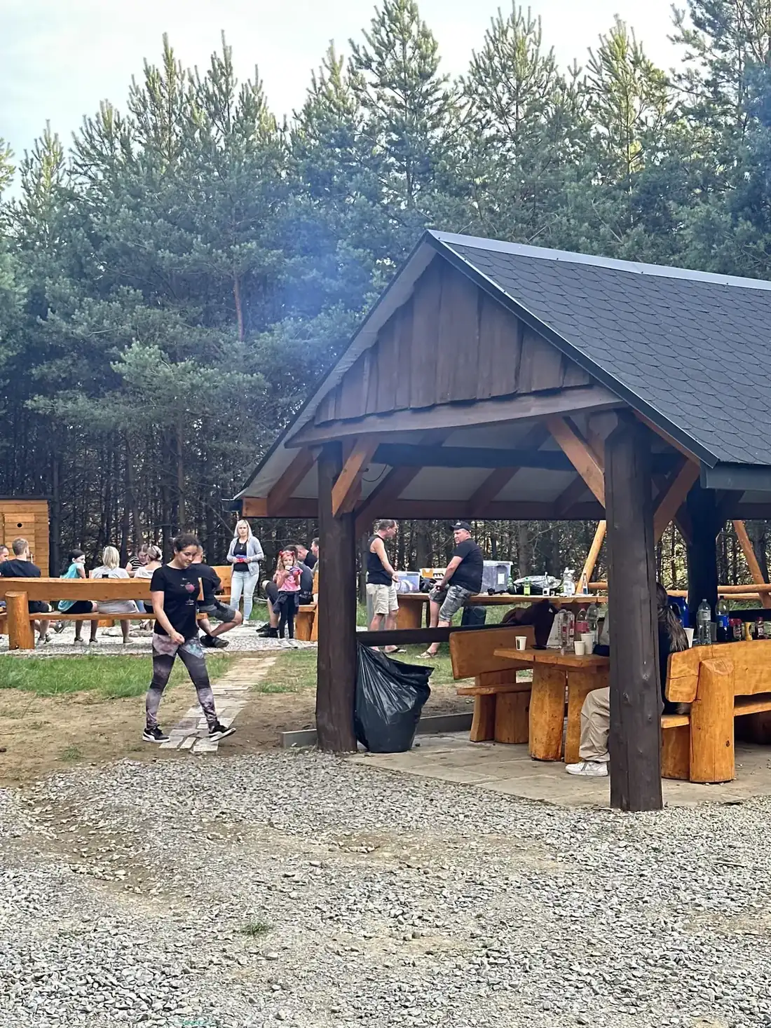 Drewniana altanka Arpi Paintball wieczorem, stół zastawiony przez grupę